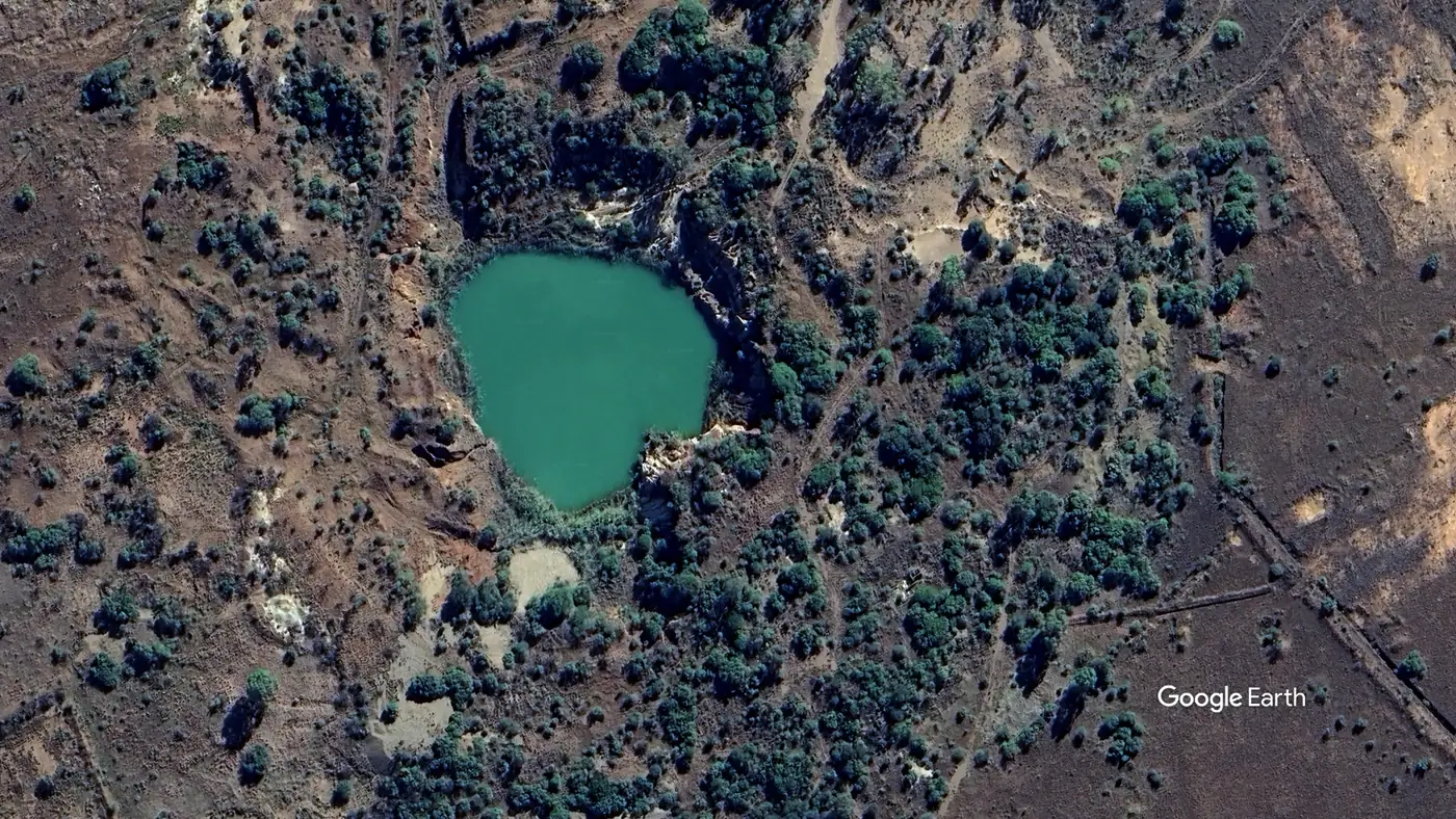 Aerial view of Pienaar's Pothole, a flooded circular working surrounded by bush and worked ground